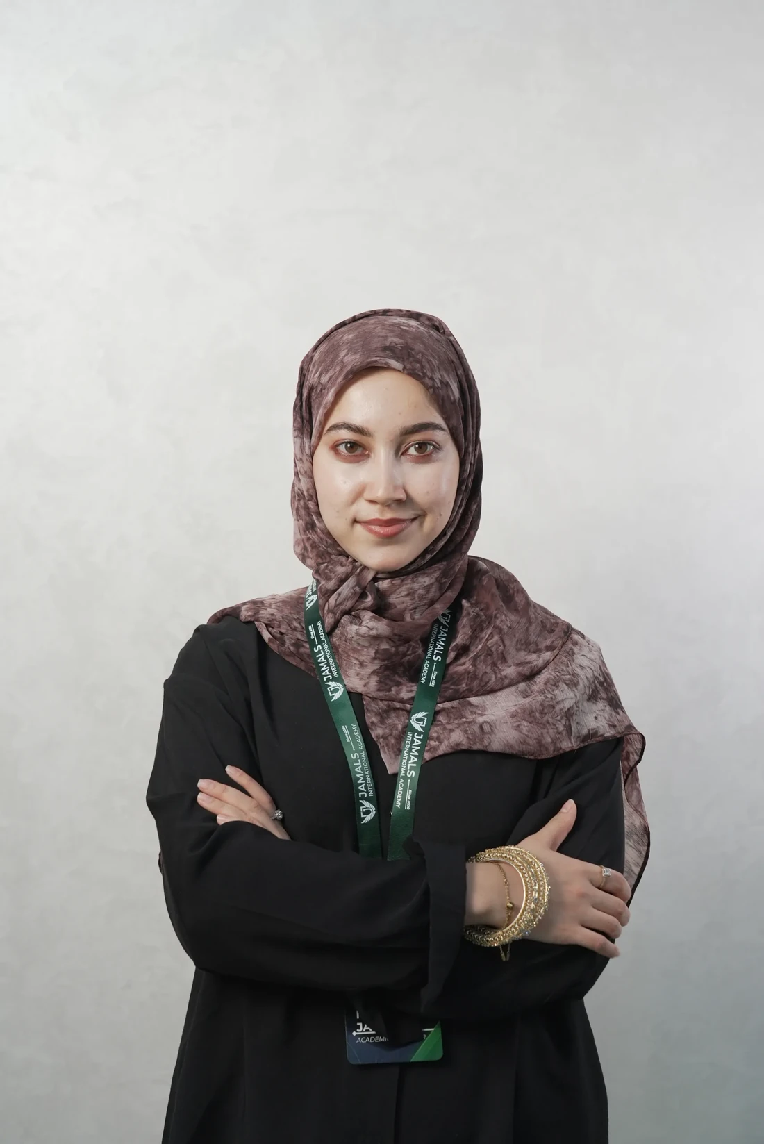 Marifat Jamal, portrait, arms folded, against a light grey wall