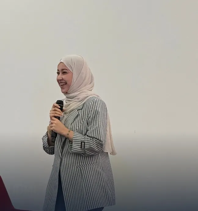 Marifat Jamal on stage, speaking into a microphone and smiling